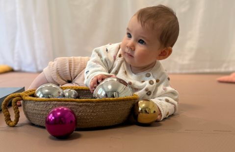 Baby spielt mit Spiegelball und Korb